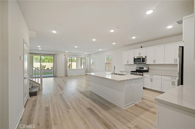 kitchen with recessed lighting, a sink, light wood-type flooring, white cabinets, and appliances with stainless steel finishes