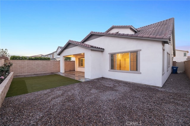back of house featuring a fenced backyard, stucco siding, a tiled roof, and a patio area