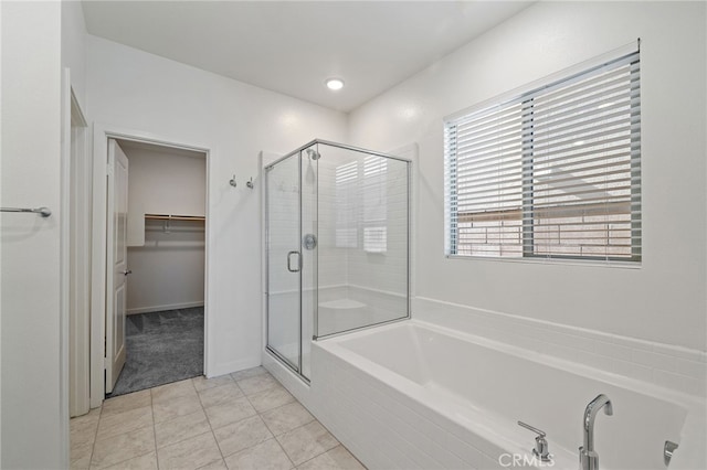 full bathroom featuring a walk in closet, a stall shower, tile patterned flooring, and a bath