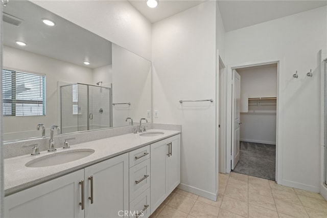 full bathroom with double vanity, visible vents, a stall shower, and a sink