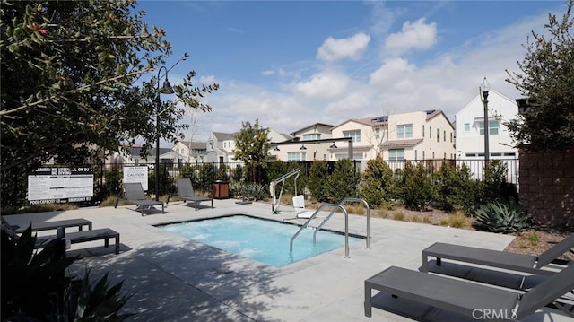 view of swimming pool with fence, a swimming pool, a patio area, and a residential view