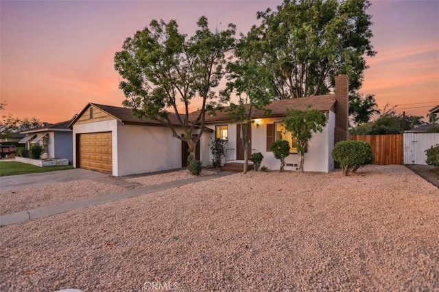 ranch-style house featuring a chimney, driveway, fence, a garage, and stucco siding
