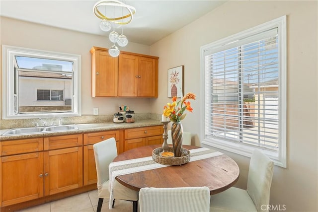 kitchen featuring brown cabinetry, light tile patterned floors, a sink, and light countertops