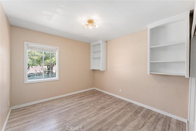 spare room with baseboards and wood finished floors
