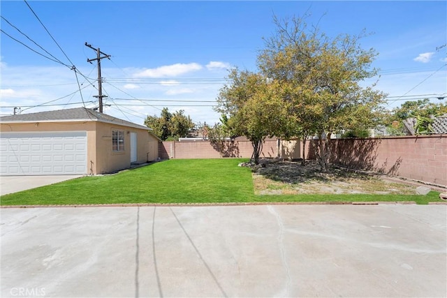 view of yard featuring a garage and a fenced backyard