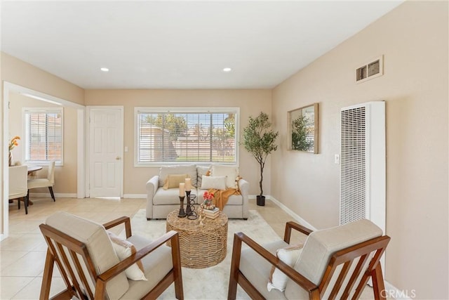 living area featuring baseboards, visible vents, light tile patterned floors, and a heating unit