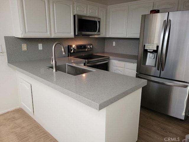 500 E Amado Rd Unit 420, Palm Springs, CA 92262 - kitchen featuring appliances with stainless steel finishes, a peninsula, a sink, white cabinets, and wood finished floors