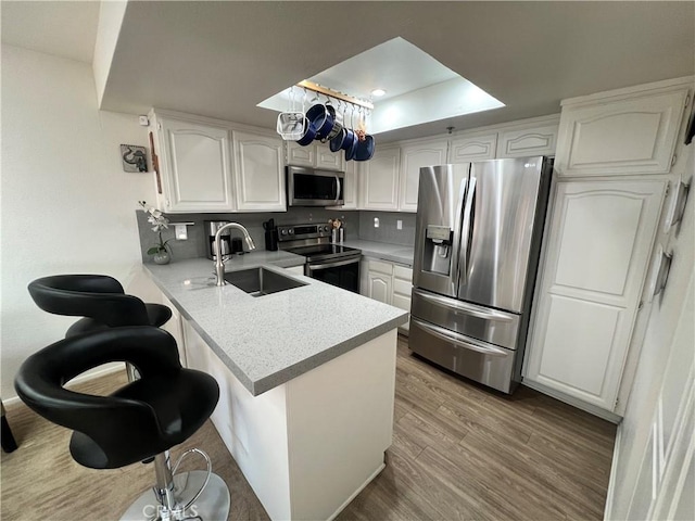 500 E Amado Rd Unit 420, Palm Springs, CA 92262 - kitchen featuring appliances with stainless steel finishes, a peninsula, white cabinetry, light wood finished floors, and a sink
