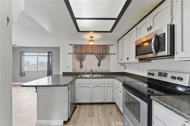 28755 Avenida Estrella, Menifee, CA 92587 - kitchen with a peninsula, dark countertops, light wood-type flooring, a sink, and appliances with stainless steel finishes
