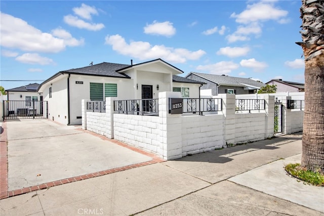 bungalow featuring roof with shingles, stucco siding, a gate, a fenced front yard, and driveway