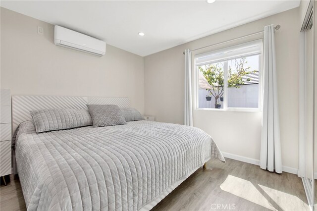 bedroom featuring an AC wall unit, recessed lighting, baseboards, and wood finished floors