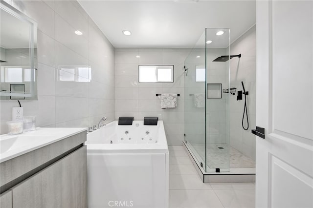bathroom with tile patterned flooring, vanity, a whirlpool tub, tile walls, and a stall shower