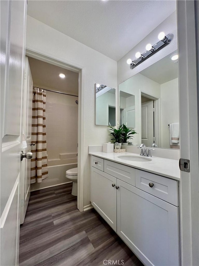 bathroom with toilet, wood finished floors, shower / tub combo, a textured ceiling, and vanity