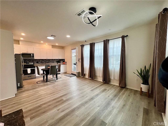 office space featuring light wood finished floors, visible vents, baseboards, and recessed lighting