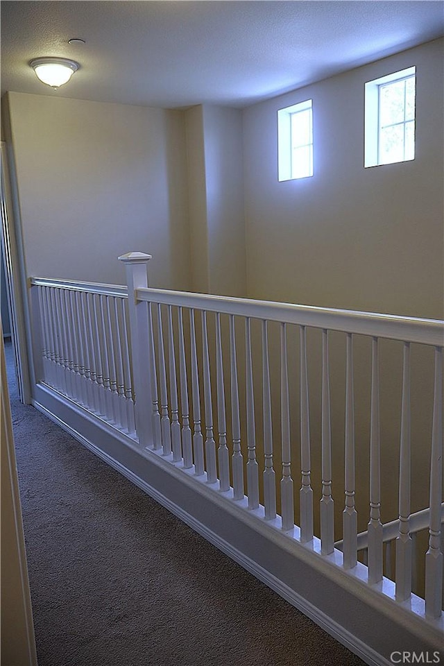 hall with an upstairs landing and carpet flooring