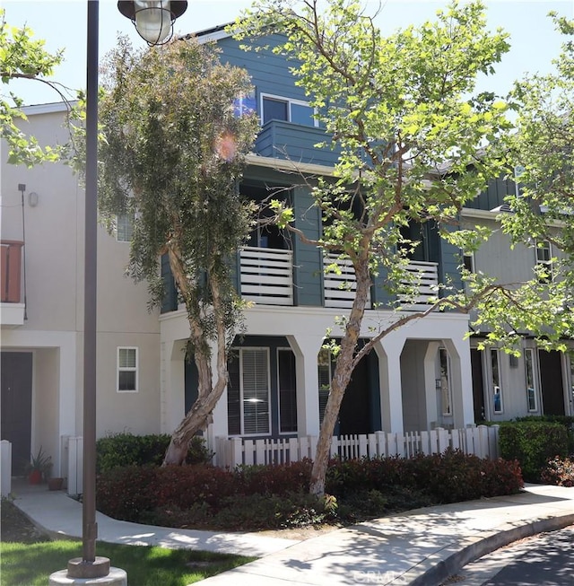 view of property featuring covered porch, a balcony, and stucco siding