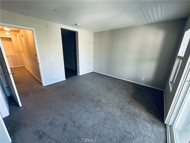 unfurnished bedroom with dark colored carpet and baseboards