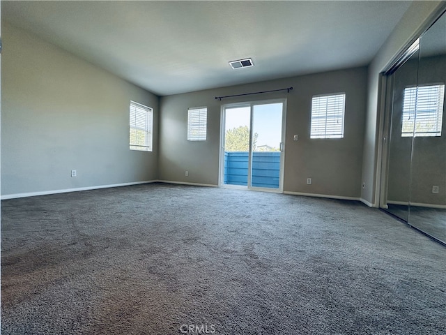 carpeted empty room featuring baseboards and visible vents