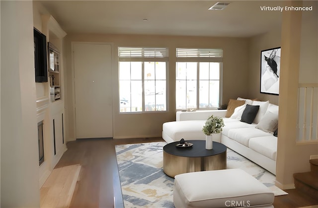 living area featuring visible vents, light wood-style flooring, and a healthy amount of sunlight
