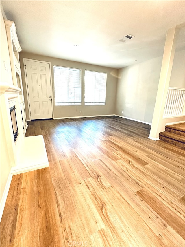 22 Platinum Cir, Ladera Ranch, CA 92694 - unfurnished living room with wood finished floors, a glass covered fireplace, stairway, and baseboards
