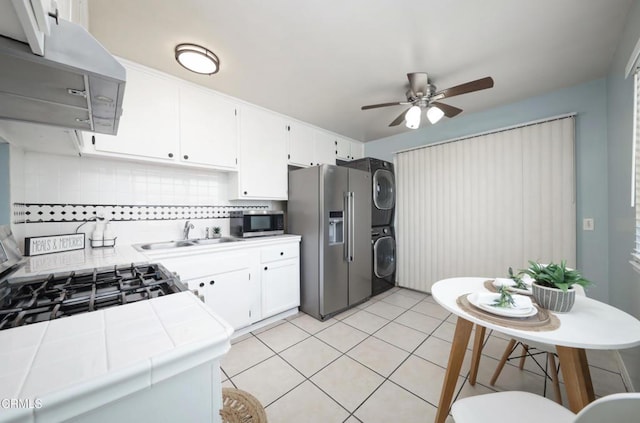 2430 Alexander St, Oxnard, CA 93033 - kitchen with stacked washer and clothes dryer, tile countertops, appliances with stainless steel finishes, wall chimney range hood, and a ceiling fan