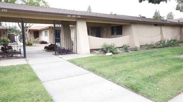 exterior space with stucco siding and a front lawn