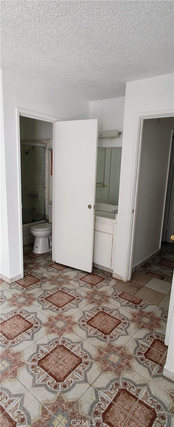 unfurnished bedroom featuring ensuite bath and a textured ceiling