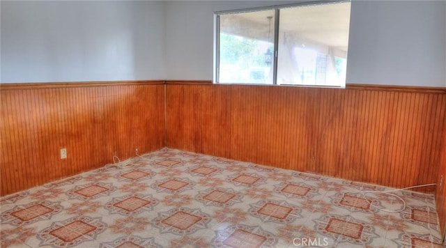 unfurnished room featuring wood walls and wainscoting