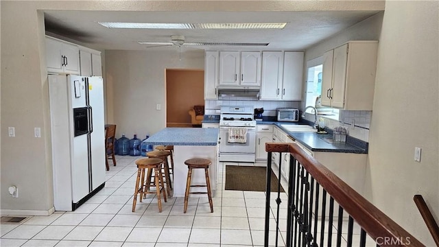 kitchen featuring backsplash, a sink, a breakfast bar, white appliances, and white cabinetry
