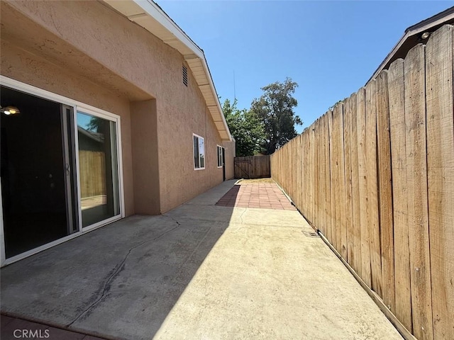 view of side of home featuring a patio, a fenced backyard, and stucco siding