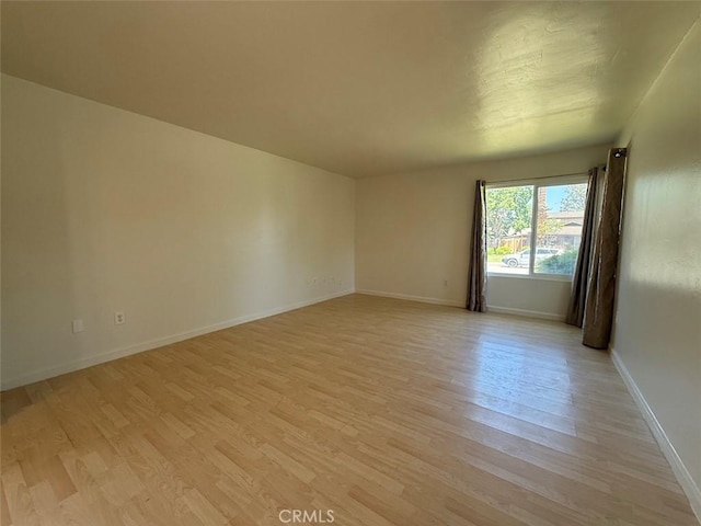 empty room with baseboards and light wood-style floors