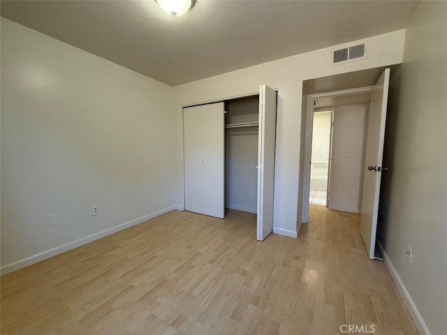 unfurnished bedroom with a closet, light wood-type flooring, visible vents, and baseboards