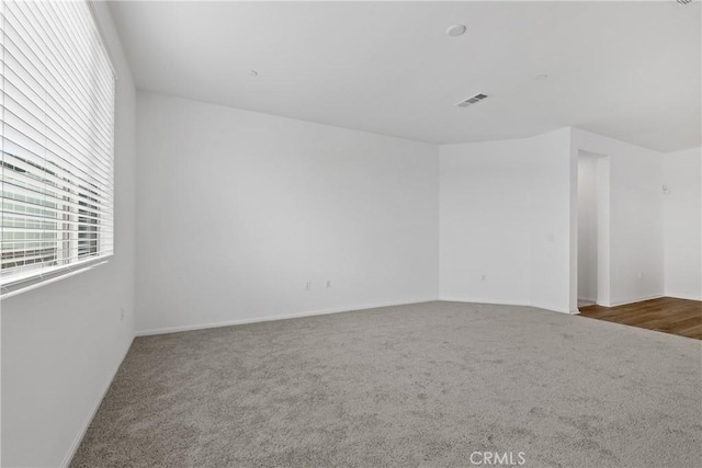 unfurnished room with visible vents, carpet floors, and baseboards