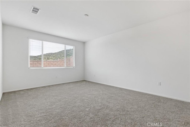 spare room with carpet, visible vents, and baseboards