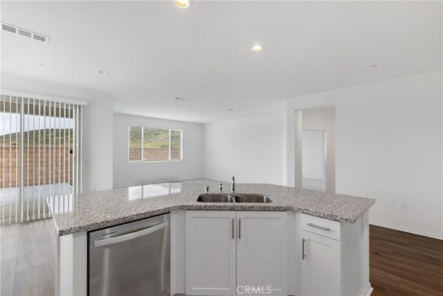 kitchen featuring light stone countertops, stainless steel dishwasher, dark wood-style flooring, a sink, and visible vents
