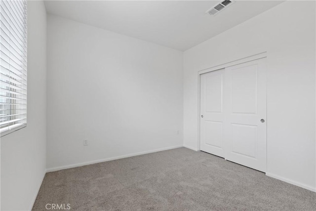 unfurnished bedroom with a closet, visible vents, carpet floors, and baseboards