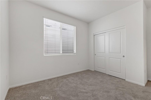 unfurnished bedroom with a closet, carpet floors, and baseboards