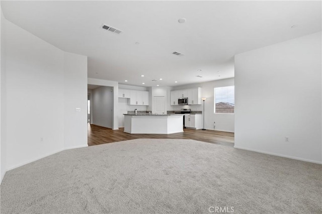 unfurnished living room featuring dark colored carpet, visible vents, recessed lighting, and baseboards