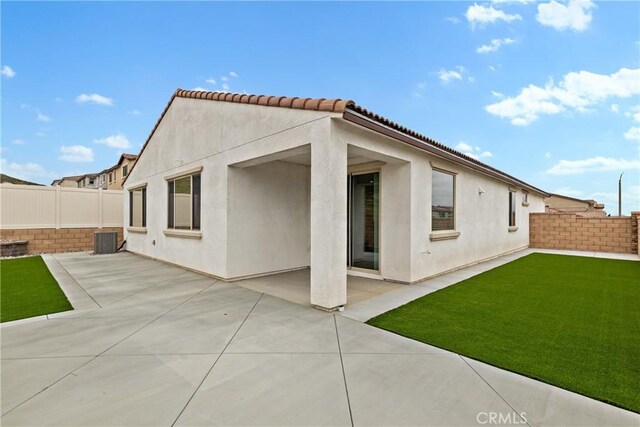 back of property with a patio, a lawn, central air condition unit, stucco siding, and a fenced backyard