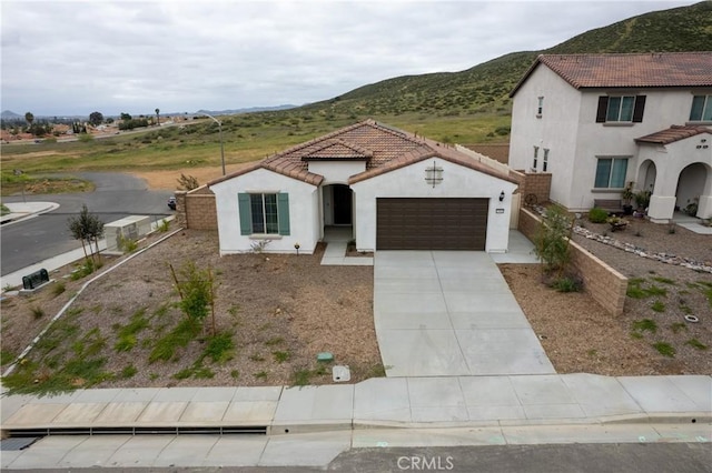 mediterranean / spanish-style house featuring an attached garage, a mountain view, and stucco siding