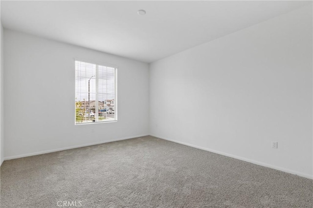 carpeted spare room featuring baseboards
