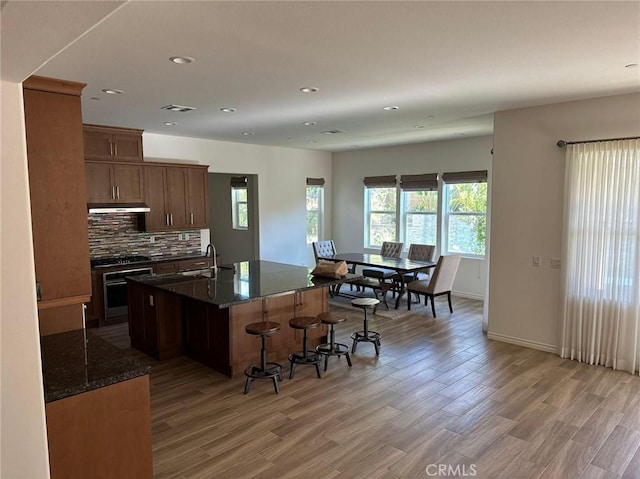 164 Newall, Irvine, CA 92618 - kitchen featuring wall oven, light wood finished floors, a kitchen breakfast bar, decorative backsplash, and under cabinet range hood