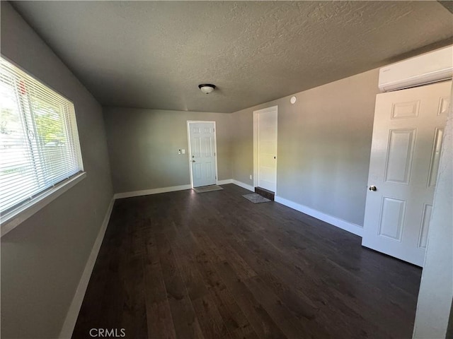 3723 Buckeye St, Clearlake, CA 95422 - empty room with a textured ceiling, baseboards, a wall mounted AC, and dark wood-type flooring