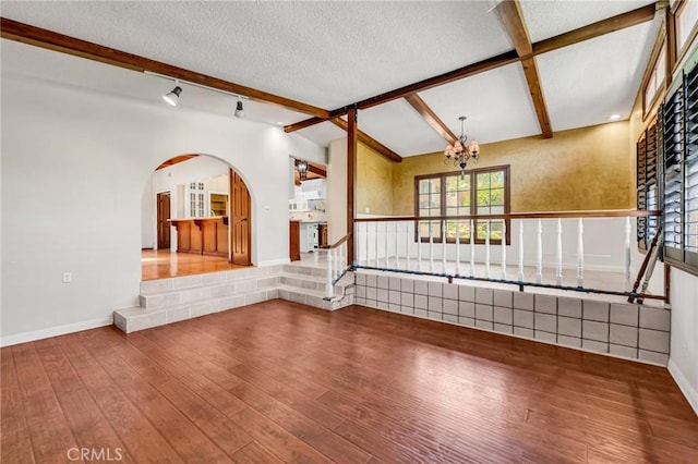 1341 E Harvest Moon St, West Covina, CA 91792 - unfurnished living room featuring hardwood / wood-style floors, beamed ceiling, a wainscoted wall, arched walkways, and a textured ceiling