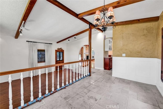 1341 E Harvest Moon St, West Covina, CA 91792 - unfurnished room with track lighting, a textured ceiling, beam ceiling, a chandelier, and stone tile floors