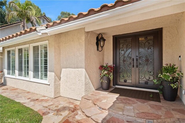 view of exterior entry with stucco siding and french doors