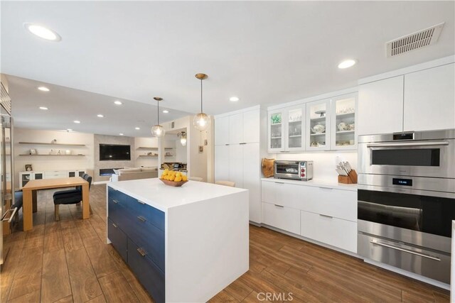 kitchen featuring double oven, visible vents, modern cabinets, a warming drawer, and a kitchen island