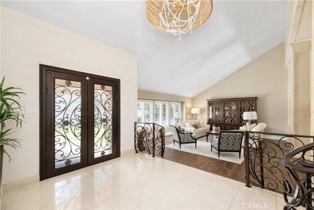 foyer entrance with french doors, an inviting chandelier, and high vaulted ceiling