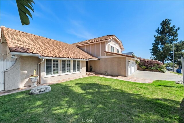 back of house featuring stucco siding, an attached garage, concrete driveway, and a lawn