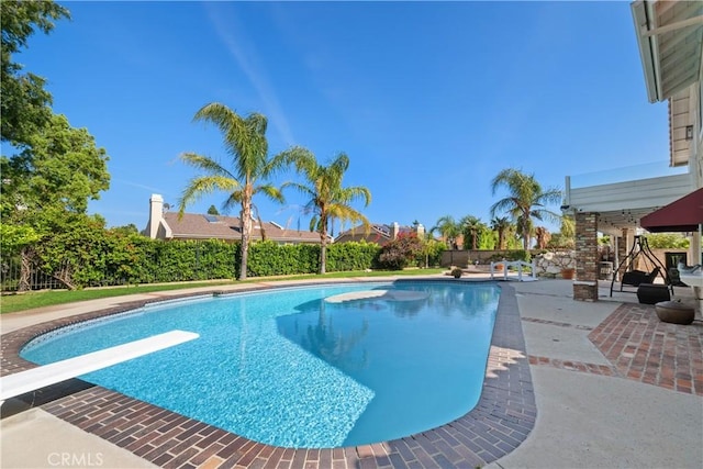 view of swimming pool featuring a diving board, a patio, and a fenced in pool